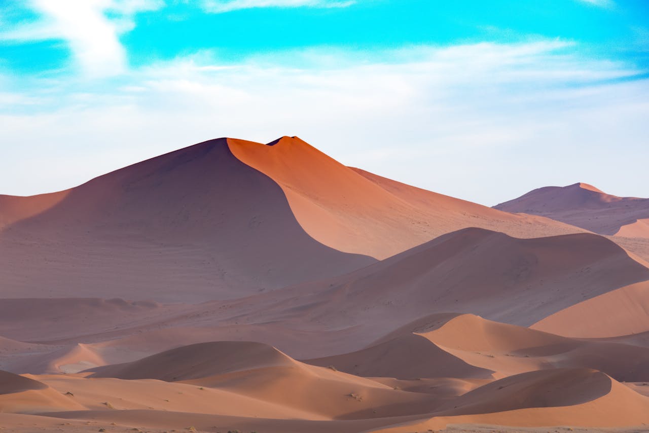 Home Capture the serene beauty of Namibian sand dunes under a vibrant sky. Perfect for desert-themed designs.